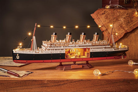 Sfeervolle presentatie van de Robotime 1912 - Eternal Atlantic Voyager, houten modelbouw van een vintage stoomschip met een uitsnede in de romp waarin retro interieur te zien is