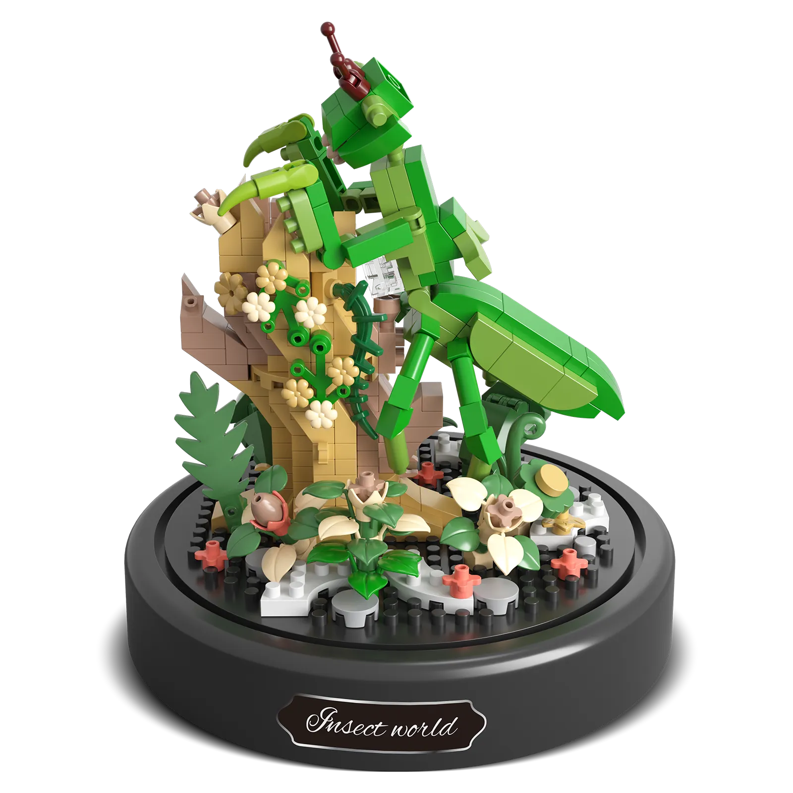 Productfoto van de Balody miniblocks bidsprinkhaan op een tak met bloemetjes en een met plantjes bedekte grond, onder een stolp