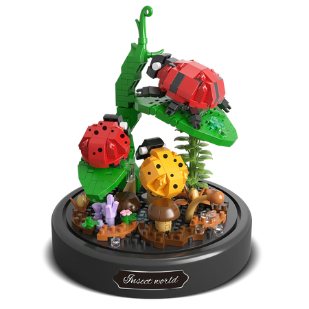Productfoto van de Balody miniblocks twee rode en een geel lieveheersbeestje op een stengel met bladeren en paddestoeltjes op de grond, onder een stolp