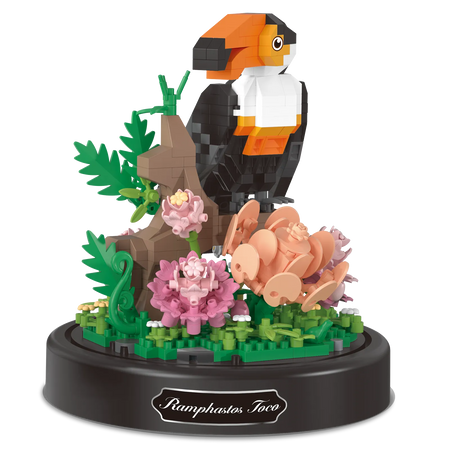 Productfoto van de Balody miniblocks op een tak zittende toekan met bloemen, onder een stolp