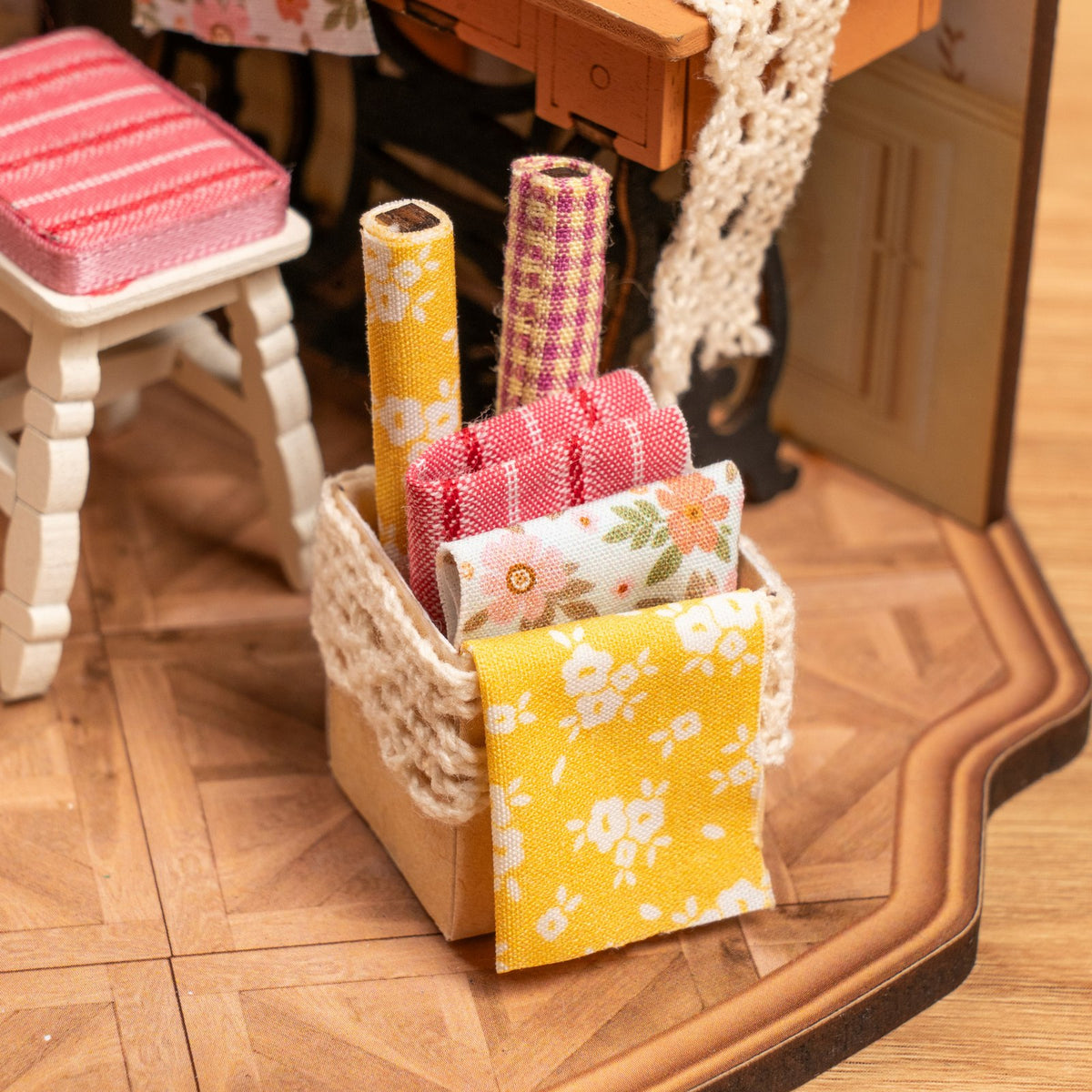 Close-up van een doos met lappen en rollen stof in de Robotime Elsa’s Tailoring