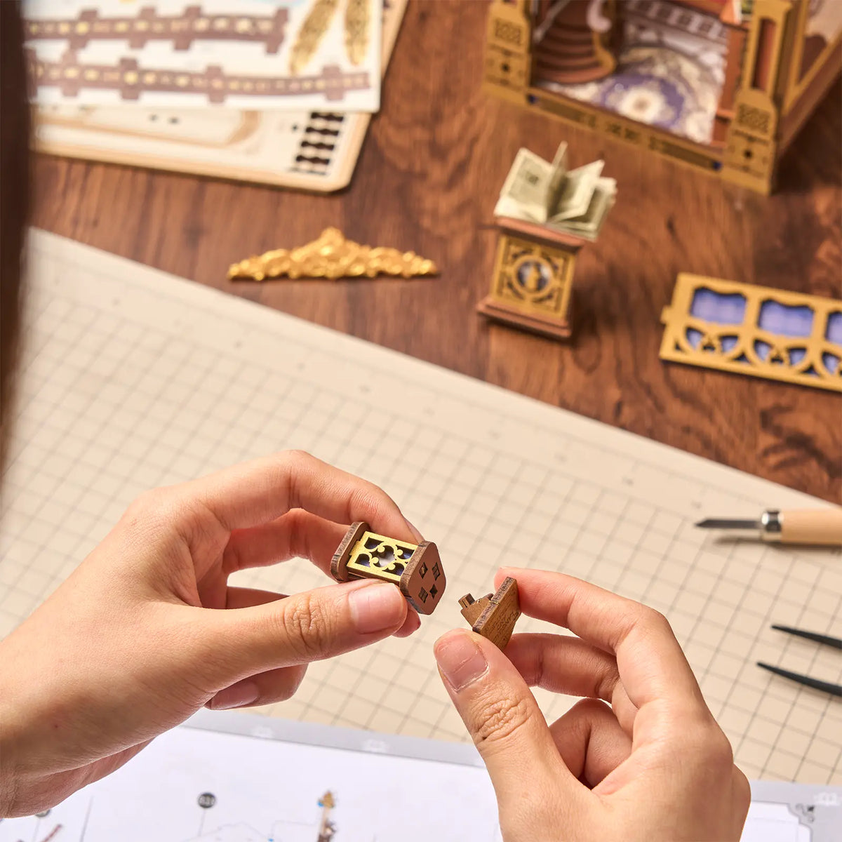 Een persoon zet een onderdeel van de Robotime Library of Wonders in elkaar