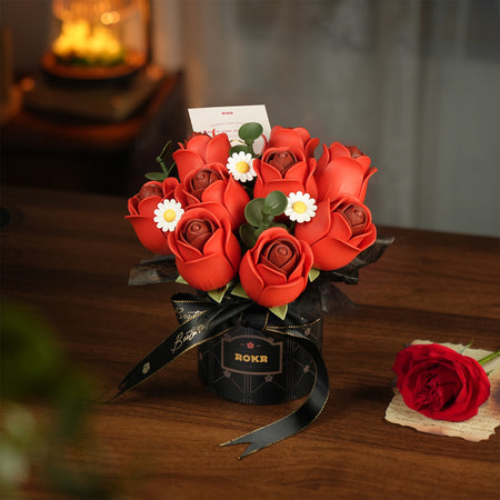Sfeervolle presentatie van de Robotime Red Rose Bouquet, kunststof bouwpakket van een boeket rode rozen en witte madeliefjes in een zwarte vaas met zwart lintje erom