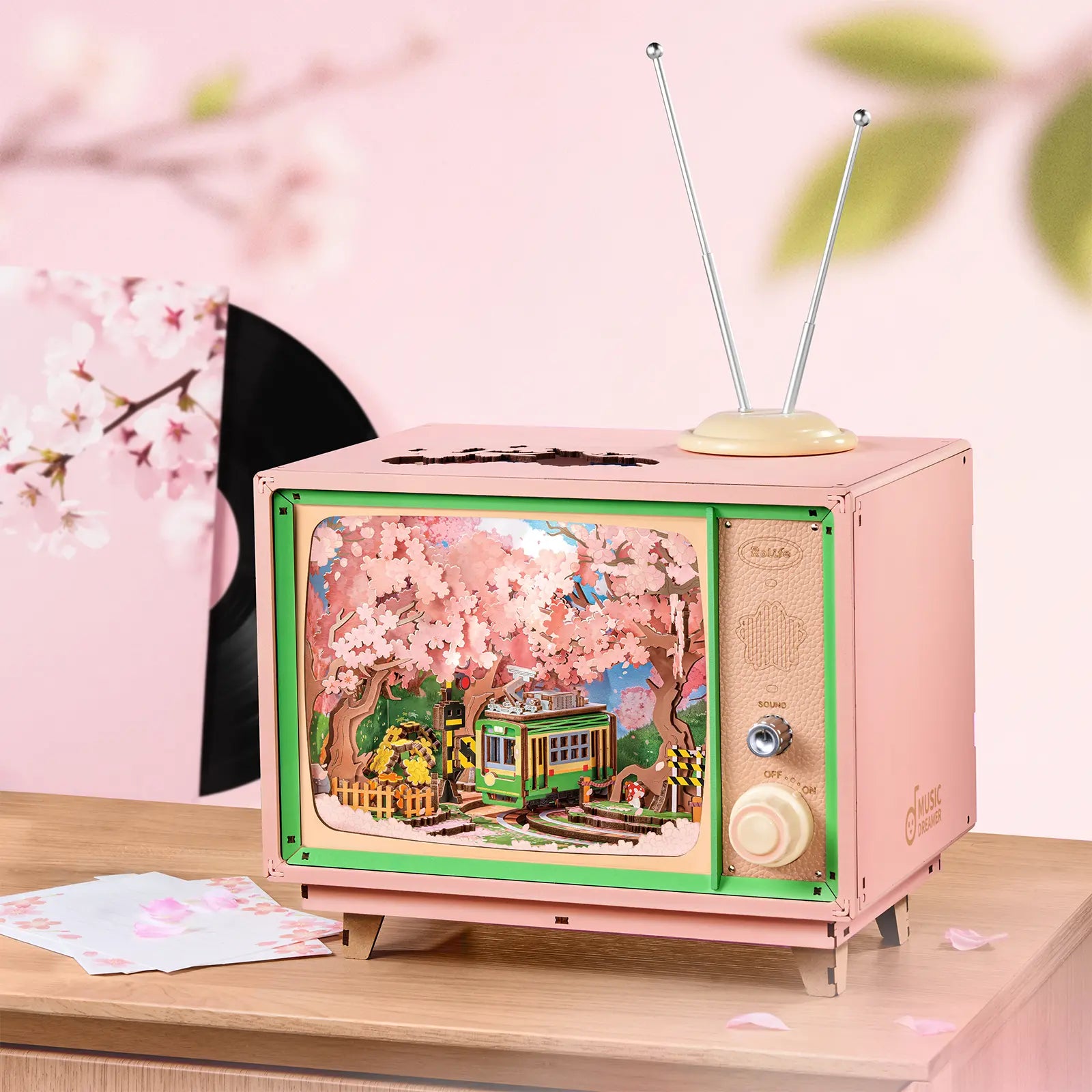 Sfeervolle presentatie van de Robotime Sakura Dreamy Tour, houten bouwpakket van een tv’tje met daarin een rondrijdend trammetje