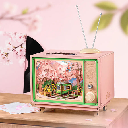 Sfeervolle presentatie van de Robotime Sakura Dreamy Tour, houten bouwpakket van een tv’tje met daarin een rondrijdend trammetje