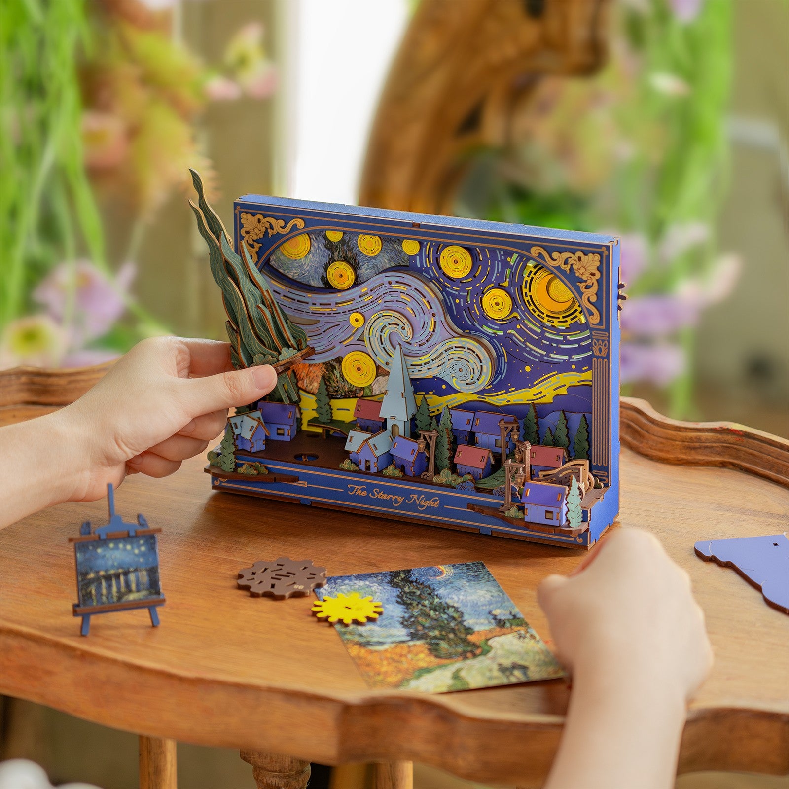 Een persoon bouwt het laatste gedeelte van de Robotime The Starry Night