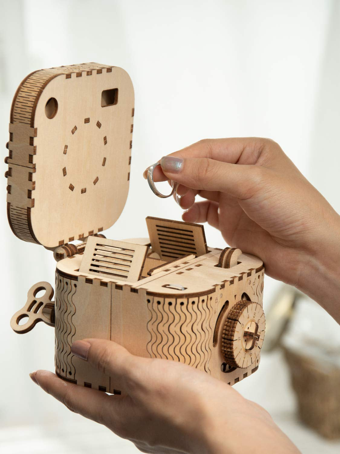Sfeerfoto van de geopende Robotime Treasure Box met iemand die een ring op wil bergen in het geheime vakje